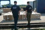 funkcjonariusz służby celnej i funkcjonariusz straży granicznej stoją przy kartonowych pudłach