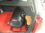 Czarna podłużna butla/zbiornik w bagażniku pojazdu 