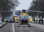 Na jezdni stoi helikopter LPR. Za nim kolizja pojazdów. 